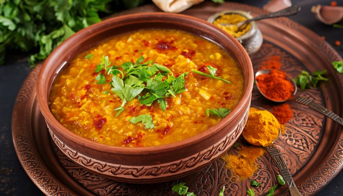 Indian dal. Traditional Indian soup lentils.  Indian Dhal spicy curry in bowl, spices, herbs, rustic black wooden background. Authentic Indian dish. Overhead